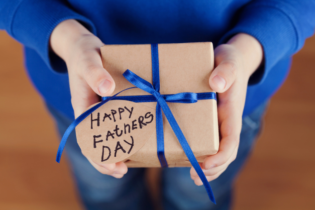 Childrens hands holding gift, present with tag Happy fathers day
